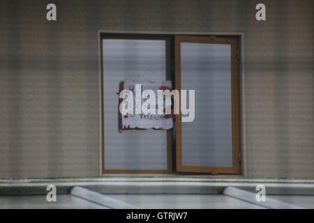 Milton Ernest, Bedford, Regno Unito. 10 settembre 2016. Un segno scritto a mano che recita "Aiutaci. Vogliamo rilasciare” è tenuto attraverso una finestra parzialmente aperta, suggerendo un appello per la libertà o l’assistenza. L'immagine evoca temi di confinamento, protesta o angoscia. Centinaia di manifestanti protestano contro il recinto del centro di detenzione Yarls Wood chiedendo la chiusura della struttura. Penelope Barritt/Alamy Live News Foto Stock