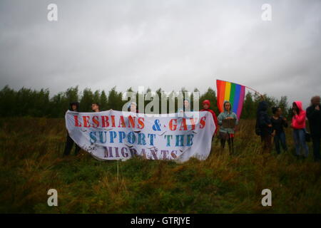 Milton Ernest, Bedford, Regno Unito. 10 settembre 2016. Un gruppo di manifestanti si trova in un campo erboso con uno striscione che recita "Lesbians & Gays Support the Migrants" accanto a una bandiera arcobaleno. La protesta evidenzia il sostegno intersettoriale tra le comunità LGBTQ+ e i diritti dei migranti. Centinaia di manifestanti protestano contro il recinto del centro di detenzione Yarls Wood chiedendo la chiusura della struttura. Penelope Barritt/Alamy Live News Foto Stock