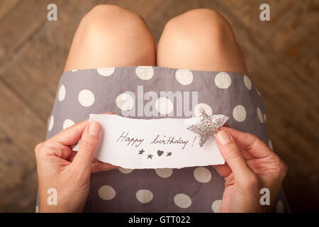 Mano che tiene una nota di carta con il messaggio buon compleanno su di esso Foto Stock