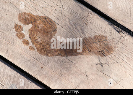 Stampa ad umido di un piede umano dopo il ponte di legno. Primo piano. Nessuno attorno a. Foto Stock