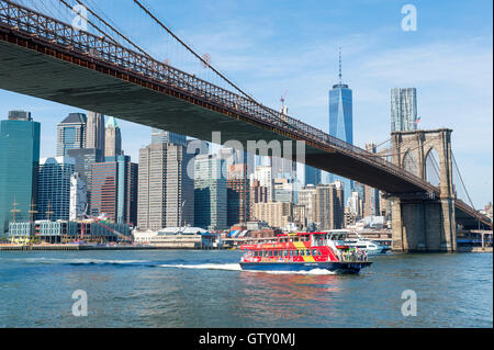 NEW YORK CITY - Agosto 27, 2016: Un vivacemente colorato traghetto porta i turisti sotto il ponte di Brooklyn per un viaggio intorno a Manhattan. Foto Stock