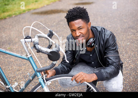 Giovane uomo il controllo dei suoi pneumatici di biciclette. Foto Stock