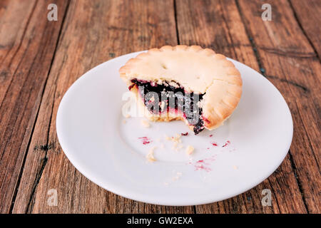 Tritare crostate con marmellata di frutti di bosco interno su una piastra bianca sul tavolo di legno Foto Stock