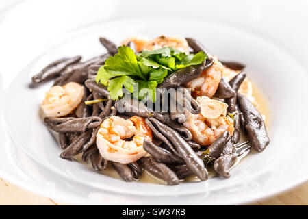 Piatto di frutti di mare, pasta nera con Gamberi serviti al ristorante Foto Stock