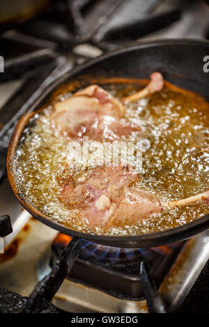 Gambe di anatra friggere in una padella Foto Stock