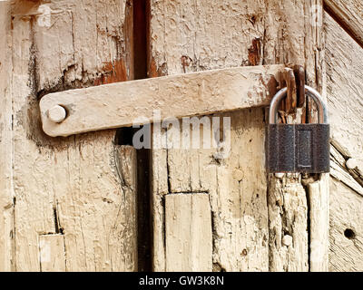 Vecchia chiusa weathered porta in legno con il lucchetto su di esso Foto Stock