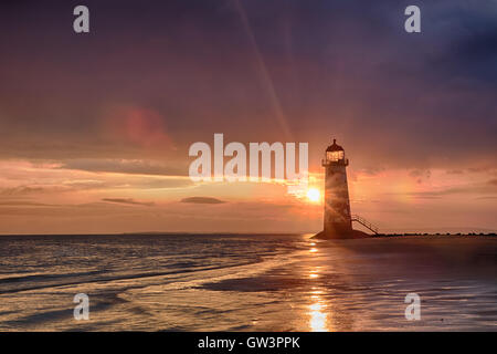 Vista del Talacre Lighthouse in Galles a sunrise vicino al mare. Blu cielo e riflessioni sulla sabbia Foto Stock