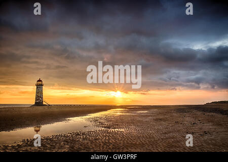 Vista del Talacre Lighthouse in Galles a sunrise vicino al mare. Blu cielo e riflessioni sulla sabbia Foto Stock