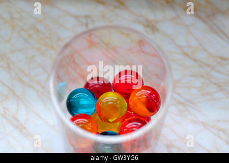 Multicolore perle di vasca da bagno in un bicchiere sul bancone in un bagno. Foto Stock