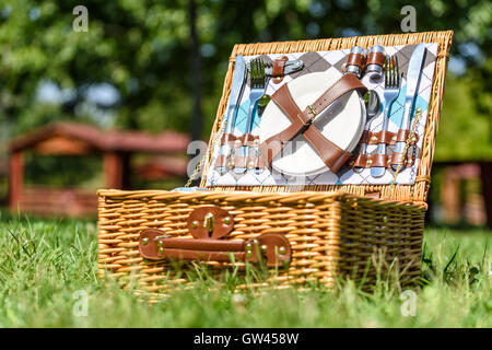 Aperto Cesto picnic con posate in primavera erba verde Foto Stock