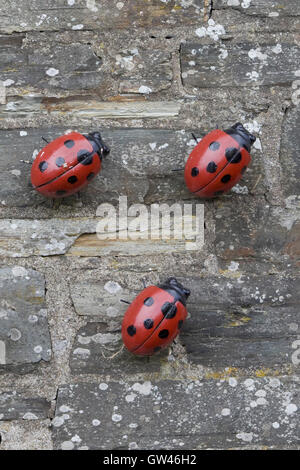 Ladybird figurine su un muro di pietra Foto Stock