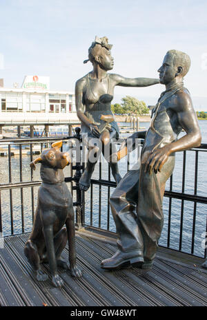 Immigrato in bronzo statue sulla passerella lungomare presso la Baia di Cardiff, Cardiff, Galles, UK. Un monumento simbolico di tempi passati. Foto Stock