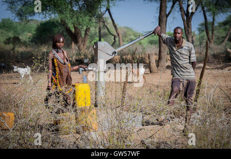 Un Hamer uomo andwoman della valle dell'Omo nel sud dell Etiopia a riempire i contenitori di acqua con acqua proveniente dalla pompa di città Foto Stock