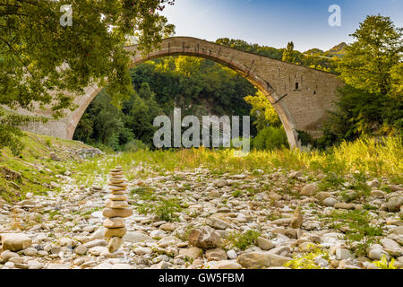 Cumulo di pietre nella parte anteriore di 500 anni hog backed Rinascimento ponte di collegamento tra due rive con singolo span in campagna italiana Foto Stock