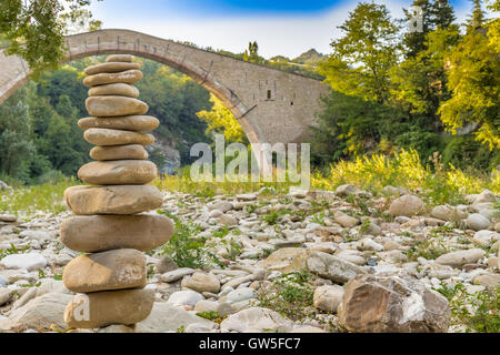 Cumulo di pietre nella parte anteriore di 500 anni gobbo Rinascimento ponte di collegamento tra due rive con singolo span in campagna italiana Foto Stock