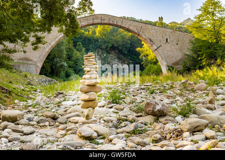 Cumulo di pietre nella parte anteriore di 500 anni gobbo Rinascimento ponte di collegamento tra due rive con singolo span in campagna italiana Foto Stock