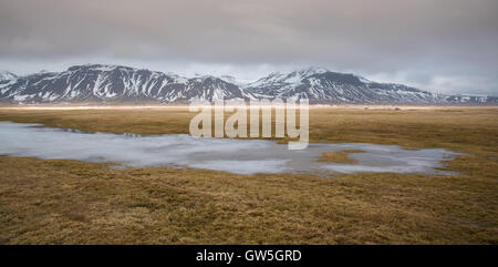 Tipico islandese drammatico paesaggio con lago ghiacciato e montagne coperte di neve in Islanda Foto Stock