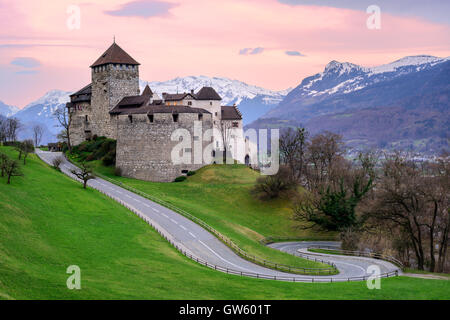 Il castello di Vaduz, la residenza ufficiale del principe di Liechtenstein, con coperte di neve montagne delle Alpi in background sul tramonto Foto Stock