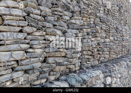 Il muro di pietre di fiume imballate in una griglia di metallo Foto Stock