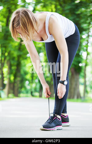 Colpo di una giovane donna di legatura lacci di lei prima di correre. Foto Stock