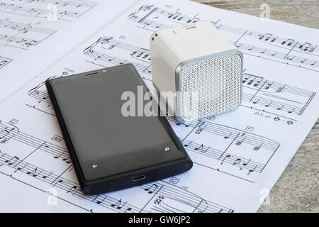 Altoparlante wireless e cellulare su di una partitura musicale. Foto Stock