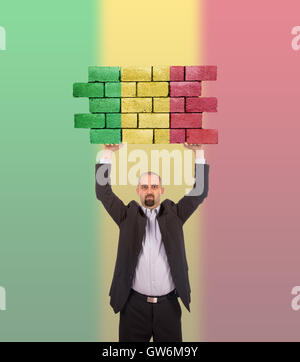 Imprenditore tenendo un grande pezzo di un muro di mattoni Foto Stock