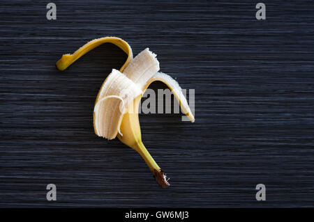 Un maturo pelato mezza banana su sfondo scuro close-up Foto Stock