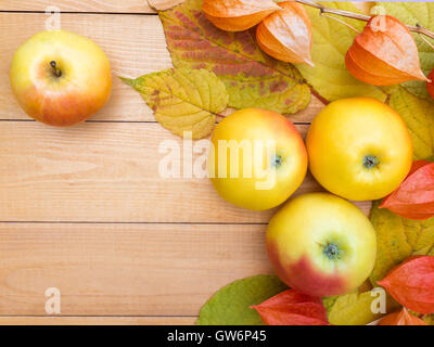 Mele, physalis lanterne e foglie di autunno su tavole di legno sfondo Foto Stock