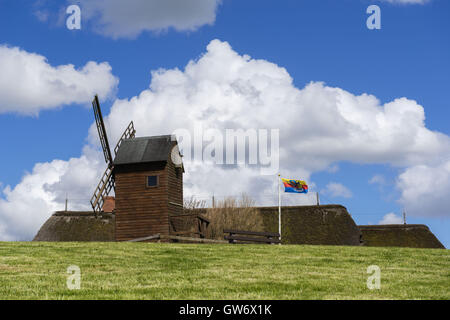 Case in paglia e un vecchio mulino a vento su un cumulo di terra, isolotto di Langeness, il frisone bandiera, Mare del Nord, Schleswig-Holstein, Germania Foto Stock