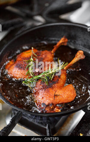 Gambe di anatra friggere in una padella Foto Stock