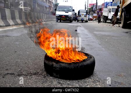 Manifestanti masterizzare pneumatico durante il Nationwide strike chiamato dai sindacati di Guwahati, India il 2 settembre 2016 Foto Stock