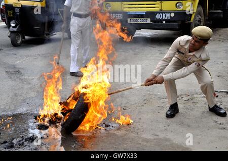 Manifestanti masterizzare pneumatico durante il Nationwide strike chiamato dai sindacati di Guwahati, India il 2 settembre 2016 Foto Stock