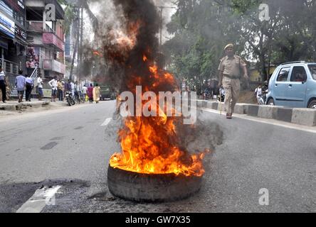 Manifestanti masterizzare pneumatico durante il Nationwide strike chiamato dai sindacati di Guwahati, India il 2 settembre 2016 Foto Stock