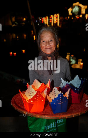 Donna anziana vendita candela galleggiante lanterne, Hoi An (Patrimonio Mondiale dell'UNESCO), Vietnam Foto Stock