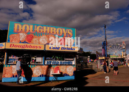 County Fair midway con ruota panoramica Ferris, giostre e bancarelle prodotti alimentari Foto Stock