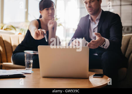 Colpo di giovane donna presentando business idea sul laptop per imprenditore. I dirigenti riuniti in un ufficio lobby discutendo nuove busin Foto Stock