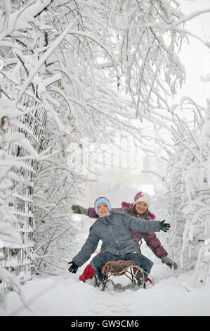 I bambini seduti sulla slitta in inverno Foto Stock