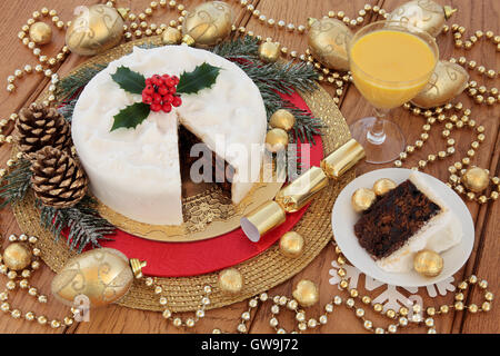 Tradizionale dolce di Natale e slice con holly, coperta di neve in inverno verde, zabaione, oro ninnolo decorazioni e stagnola avvolto Foto Stock