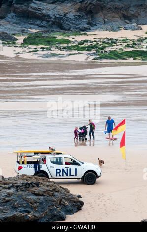 Bagnini guardando nuotatori tra rosso e giallo le bandiere di sicurezza sulla spiaggia di Treyarnon Bay in Cornovaglia. Foto Stock