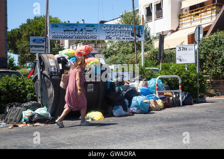 Passeggiate a piedi dalla spazzatura non riscossi in una strada di Roma, Italia Foto Stock