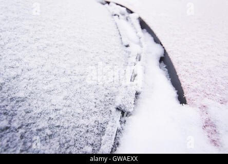 La neve e il ghiaccio ricopre auto rossa e al di fuori della finestra nel dicembre closeup. Foto Stock