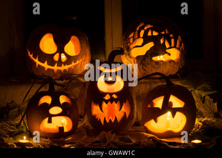Composizione della foto da cinque zucche di Halloween. Jack, mani, piangere, un ciclope e spaventati zucche contro le foglie di autunno Foto Stock