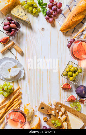 Diversi tipi di formaggi, vino e spuntini al legno bianco Foto Stock