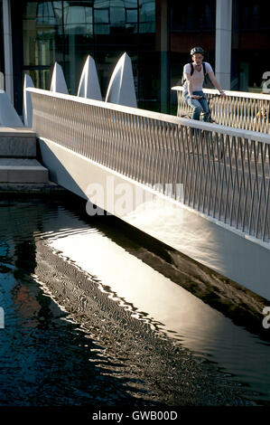 Un ciclista solitaria che attraversa il Fan Bridge, Floating Pocket Park, Paddington Basin, Londra, Regno Unito Foto Stock