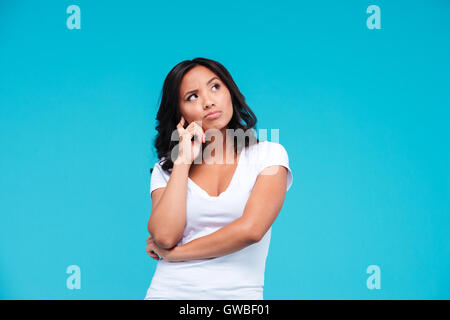 Ritratto di un pensieroso bella ragazza asiatica pensando a qualcosa di isolato su sfondo blu Foto Stock