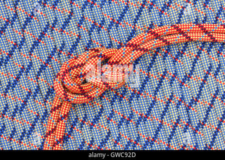 Due luminose corde colorate con una figura a otto nodi su uno sfondo di funi Foto Stock