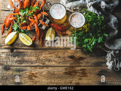 Due pinte di birra di grano e gamberi bolliti con limone e prezzemolo su un vecchio rustico in legno sfondo, vista dall'alto, spazio di copia Foto Stock