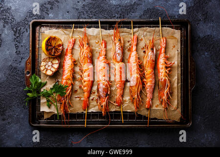 Grigliata di gamberi fritti gamberi Langostino Austral su gli spiedini sulla griglia metallica la teglia su sfondo nero Foto Stock