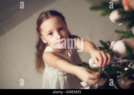 Bambina decorare albero di natale, vista dall'alto, dai toni vintage Foto Stock