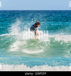Un uomo che cavalca il suo surfboard verso la riva. Famosa Bondi Beach offre una vasta gamma di attività sportive e ricreative. Foto Stock